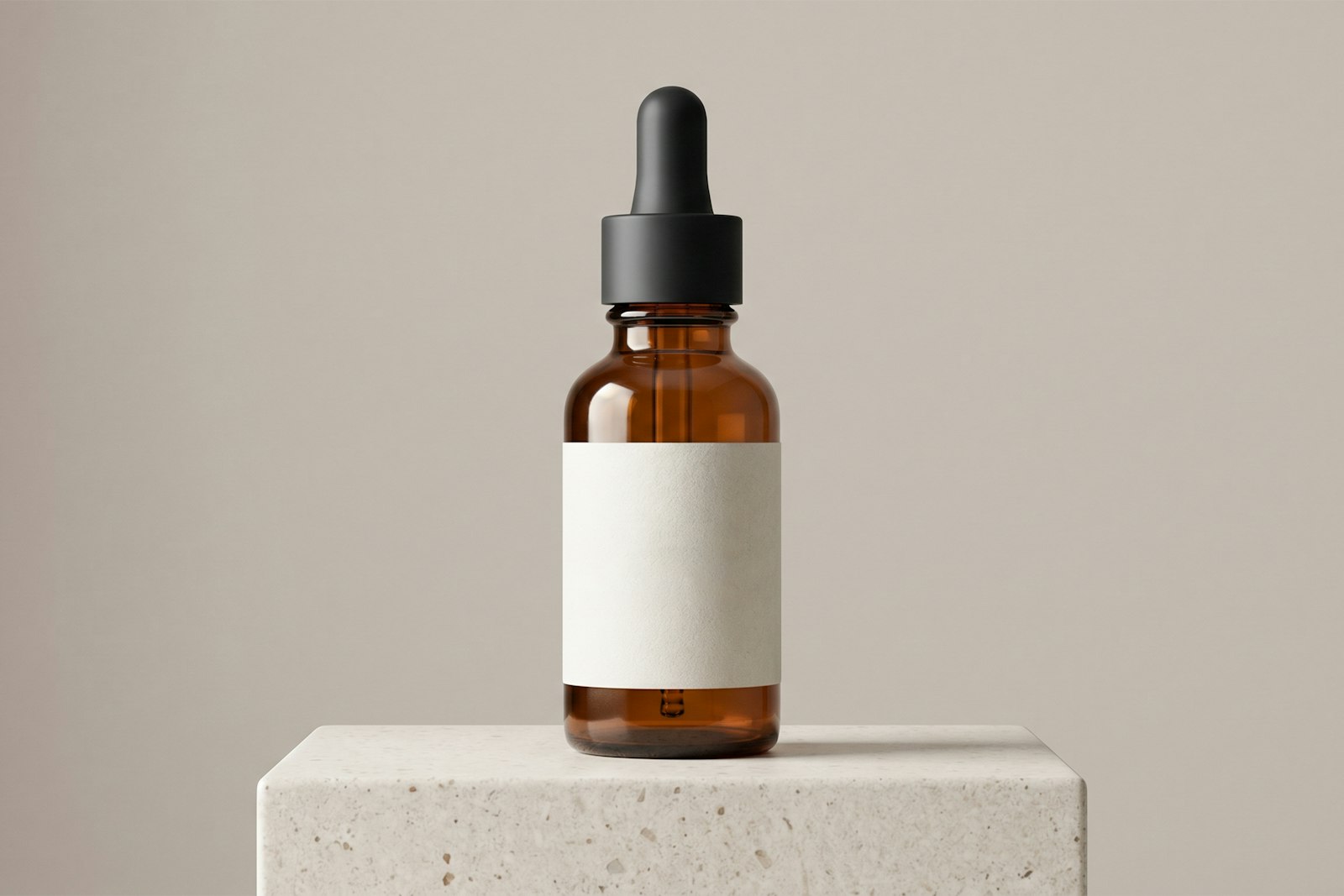 An amber glass dropper bottle with a blank label, standing on a stone plinth